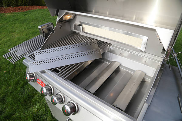 Shiny stainless steel gas grill with lid up and cooking grates removed.