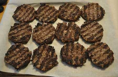 Twelve seared hamburgers on a white plate.