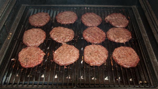 Twelve hamburgers cooking on a grill