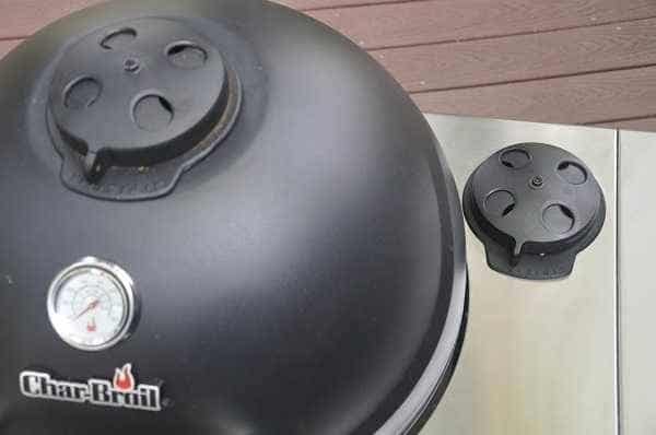 A black dome hood on the left with a round dial on top. A shiny steel shelf on the right has the same black dial.