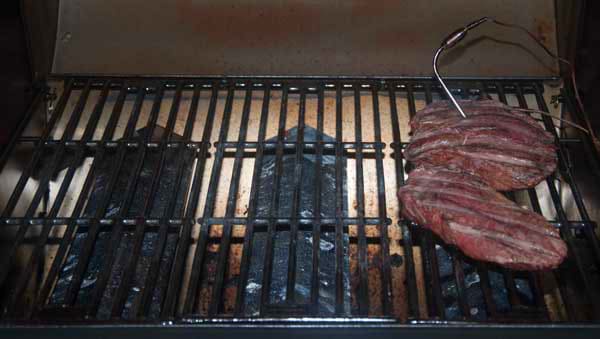 gas grill with lid open. two steaks are cooking on the right side