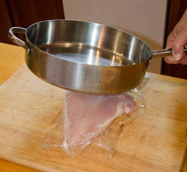 pounding chicken with a sauce pan