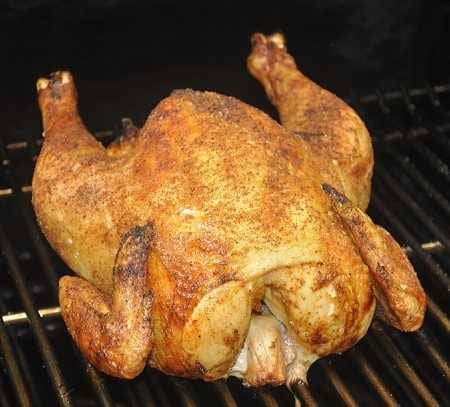 Golden brown whole chicken on a cooking grate.