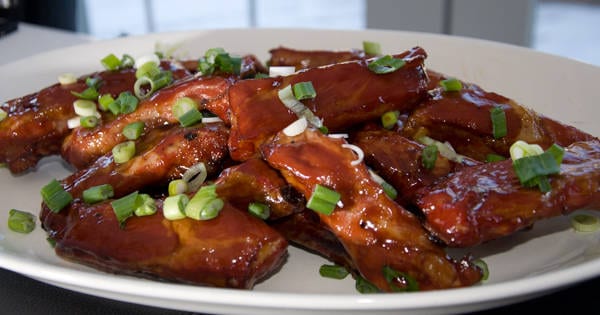 A plate of ribs garnished with chopped scallions