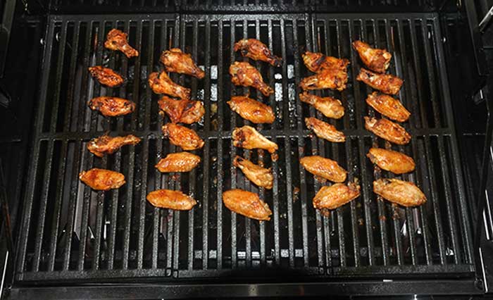 Chicken wings cooking on an outdoor grill.