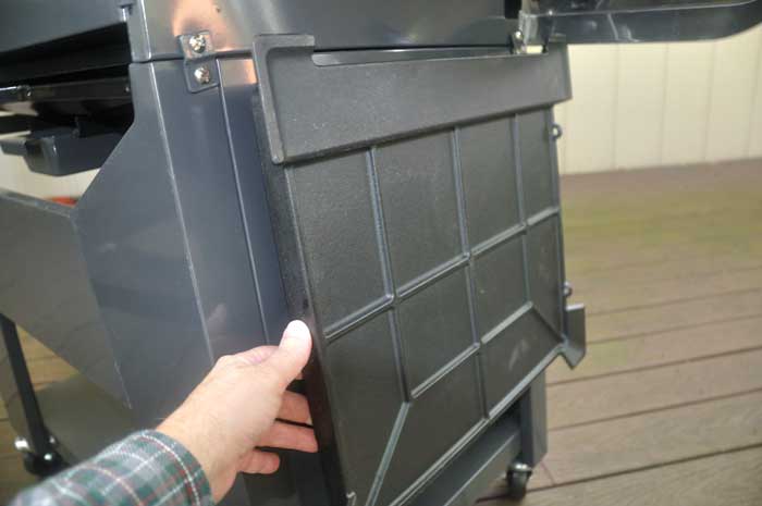 Hand lifts a large, hanging metal square object.