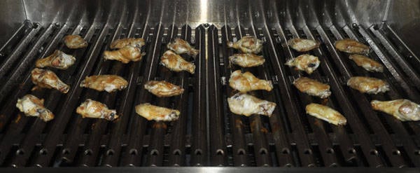 Golden brown chicken wings cooking on a bbq grill.