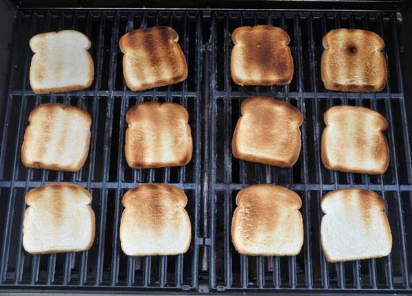 Toasted bread spread across a black, metal grill surface