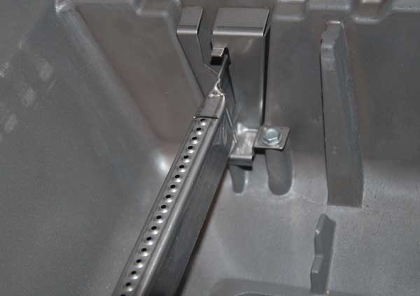 A shiny metal bar with a row of holes across the top mounted in a shiny, metal enclosure.