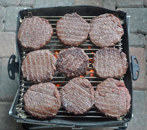 Nine hamburgers crowding a small BBQ grill grate.