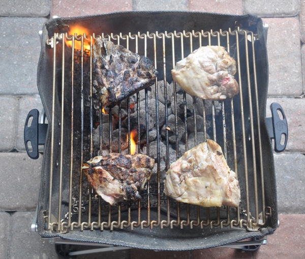 Chicken thighs on a small grill. Two are burnt.