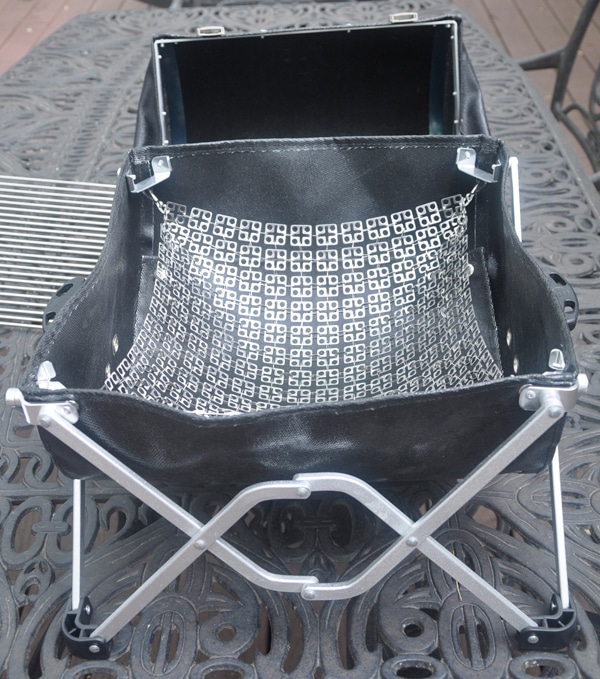 A shiny metal net placed inside a black leathery basket.