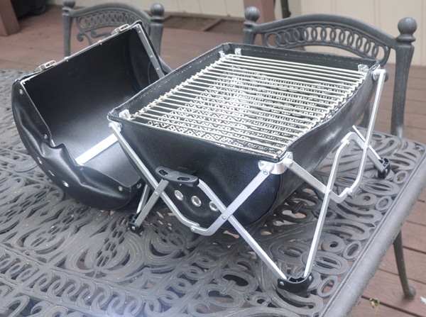 Black leather grill with a shiny metal cooking grate attached to a shiny metal fold-our stand.
