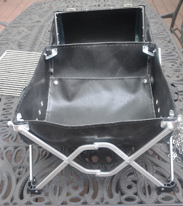 Black leathery basket on shiny fold-out stand.