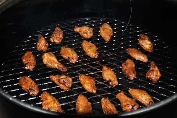 Golden brown chicken wings cooking on a round grate