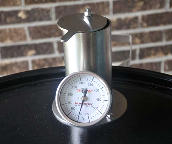 A shiny metal chimney with a thermometer attached
