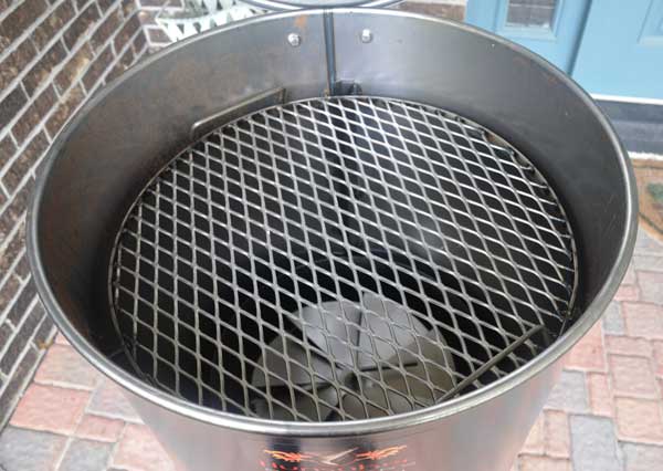 Inside of a metal barrel. A spiral metal disc and round grate are inside