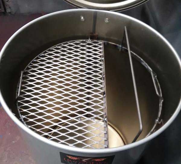 Inside of a metal barrel. A round grate with the right side cut out is placed at the top
