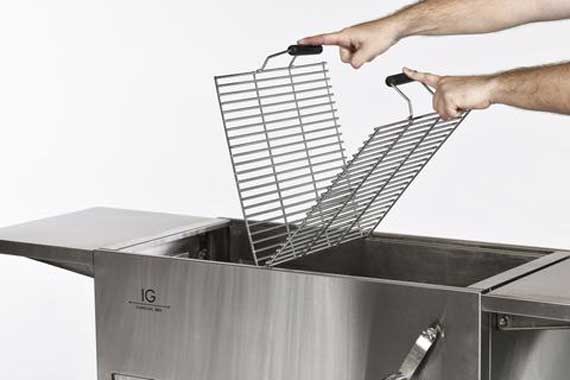 Two hands hold two steel cooking grates that are hinged together in the middle.