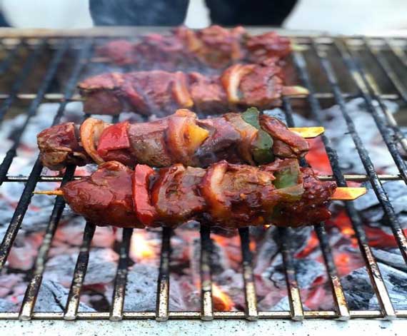 Kabobs sizzling on a charcoal grill.