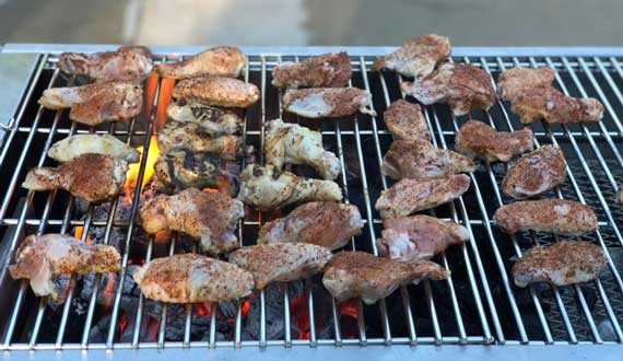 Chicken sizzling on a charcoal grill.