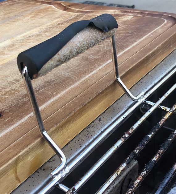 A damaged handle on a steel grill grate.