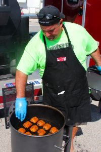 Darren Warth cheicking on chicken thighs in a drum smoker