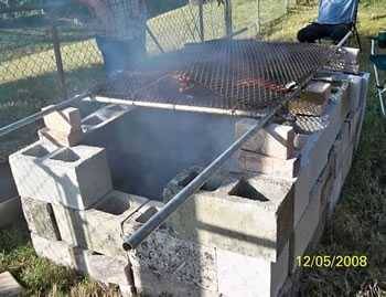 simple concrete hog pit with a chain link fence as a cooking grate