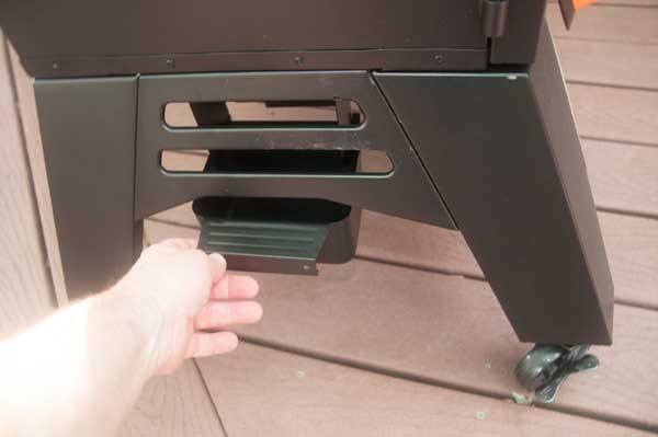 A hand pulling out a black tray from under a black cabinet