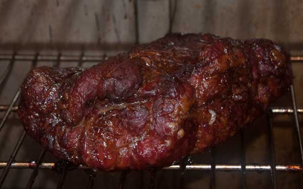 Hunk of browned, smoky meat on a cooking rack