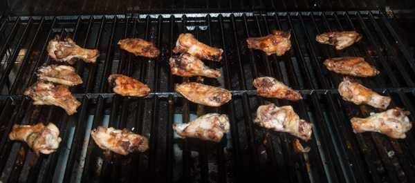 Chicken wings cooking on a BBQ grill.