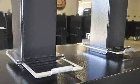 A black cabinet with two chimneys coming out of the top. In a warehouse with several black cabinets in the background.