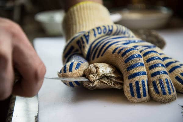 inserting the knife at the oyster's hinge