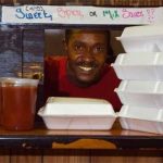 man serving boxed food through a diner kitchen window