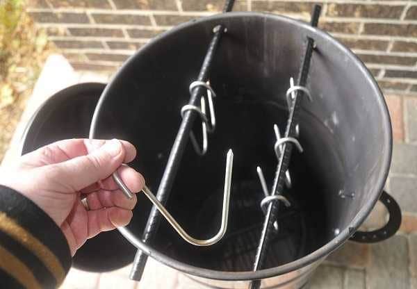 Barrel smoker from above, lid off looking at meat hanging hooks in place