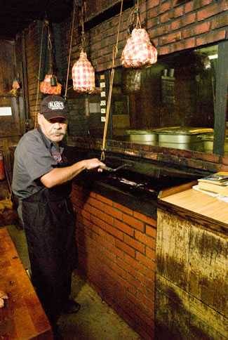 pitmaster operating pulley style barbecue pit at black's bbq
