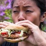 Woman eating a salmon sausage sandwich