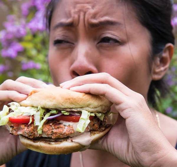 Woman eating a salmon sausage sandwich