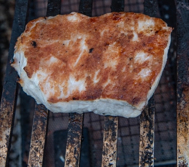 Seared pork chop on a metal cooking grate.