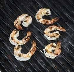 Beautifully seared shrimp on a black metal cook surface.