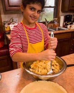 Child stirring apple pie filling