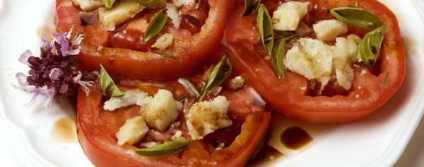 Parmesan cheese and basil leaves adorn red tomato slices