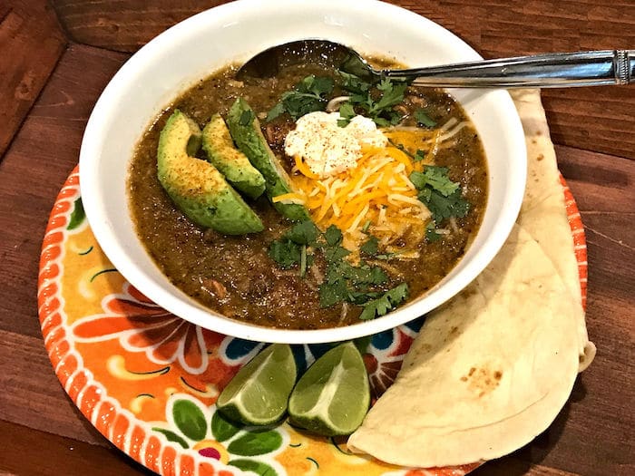 A bowl of chili topped with shredded cheese and avocado slices