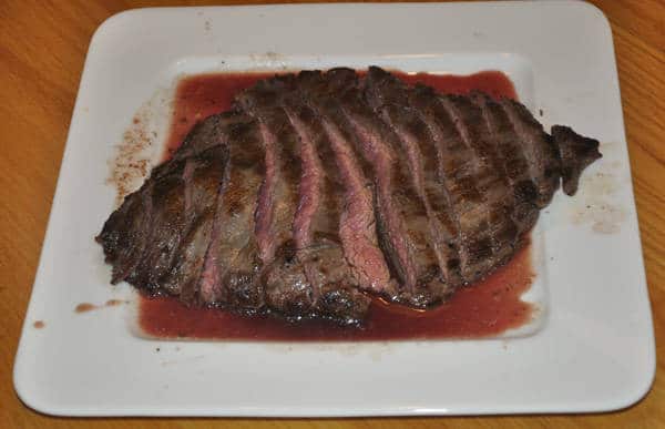 Juicy, rare steak sliced and placed on a white, square dish.