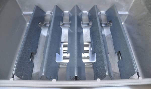 Five long, greyish, upside down V-shaped pieces of metal placed in a shiny aluminum trough.