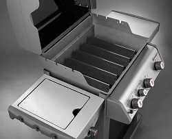 Gas grill from above. The lid is open to show metal tents covering the burners. There are shelves on both sides.