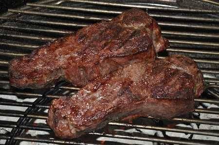 Two seared steaks on a cooking grate.