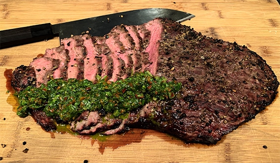 Sliced flank steak topped with chimichurri sauce