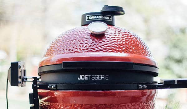 Top of a red kamado with a black metal ring sandwiched between the bottom and dome shaped lid.