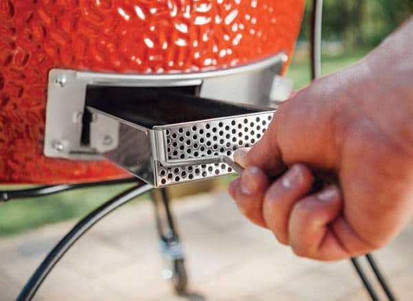 A hand pulls a metal tray from the bottom of a red object.